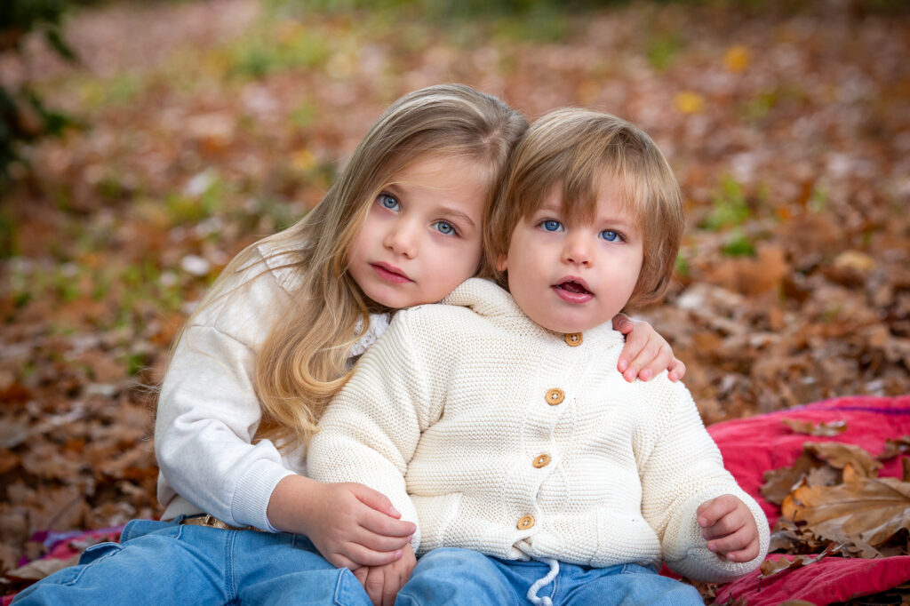 deux enfants assis dans les feuilles mortes