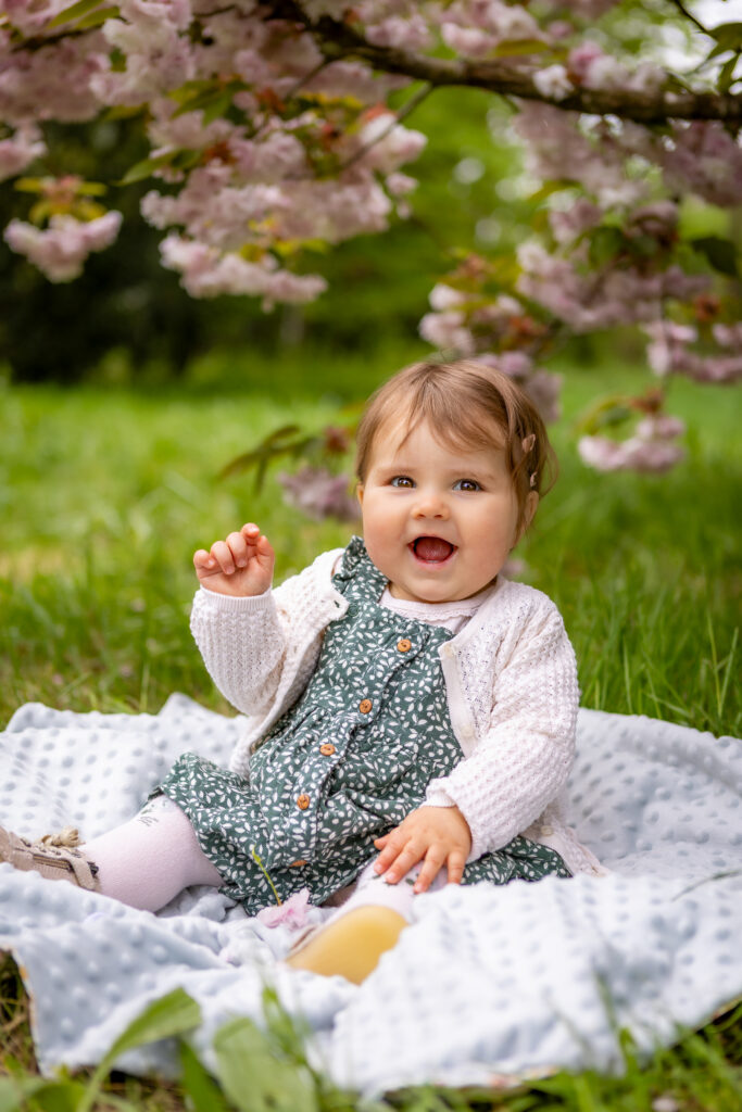 photo d'un bébé assis devant un cerisier en fleurs