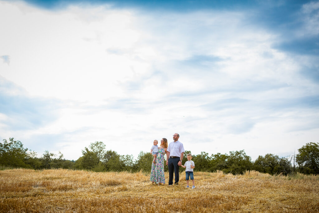séance photo en famille dans un champ de blé avec un ciel nuageux